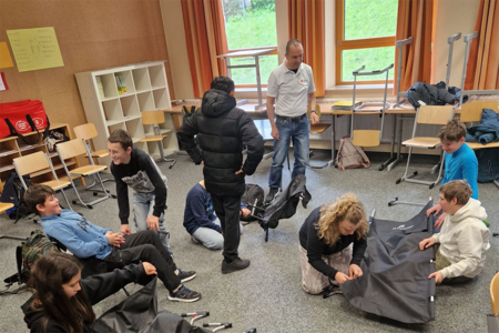 Schüler in einem Klassenraum beim Aufbau von Zelten und Hilfsmitteln.