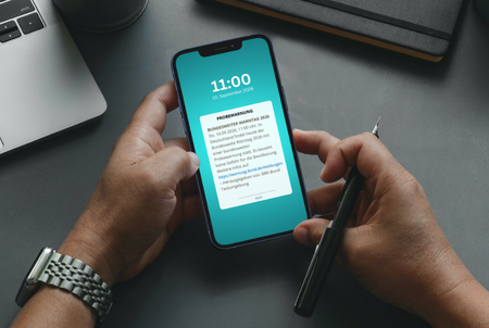 Eine Hand hält ein Smartphone mit einer Warnmeldung