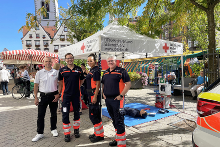 Ein Stand des DRK Biberach auf dem Wochenmarkt, davor stehen vier Mitarbeitende des DRK