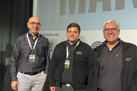 Drei Mitarbeiter des DRK Biberach stehen lächelnd auf einer Bühne.