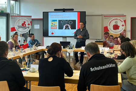 Ein Referent vom DRK hält einen Vortrag vor einer Gruppe.