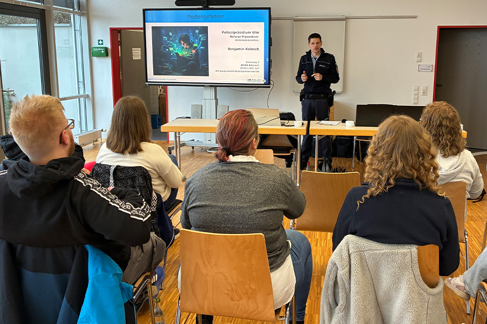 Ein Polizist hält einen Vortrag vor Ehrenamtlichen des DRK