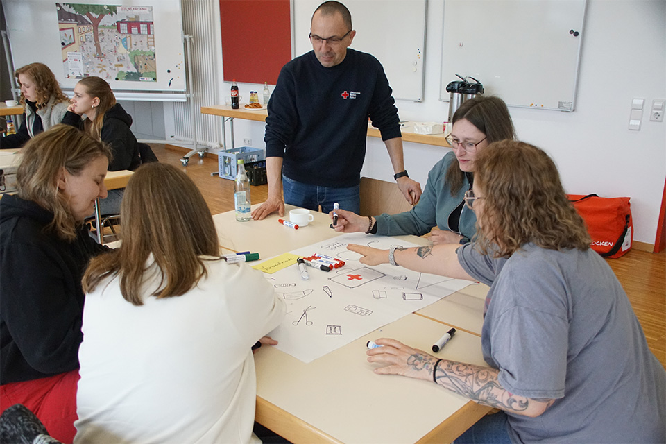 Mehrere Ehrenamtliche des DRK sitzen bei einer Gruppenarbeit