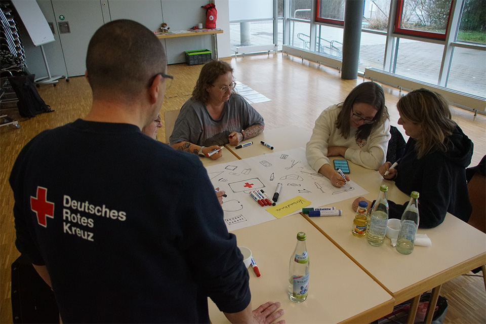 Mehrere Ehrenamtliche des DRK sitzen bei einer Gruppenarbeit