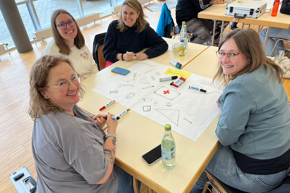 Mehrere Ehrenamtliche des DRK sitzen bei einer Gruppenarbeit