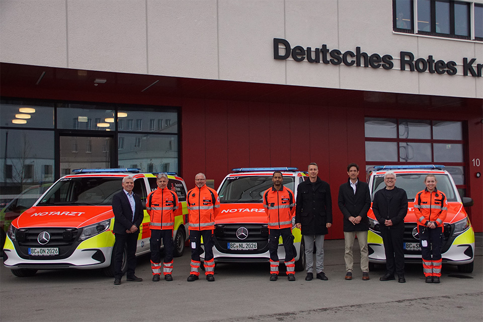 Mehrere Personen stehen vor drei Einsatzfahrzeugen beim DRK