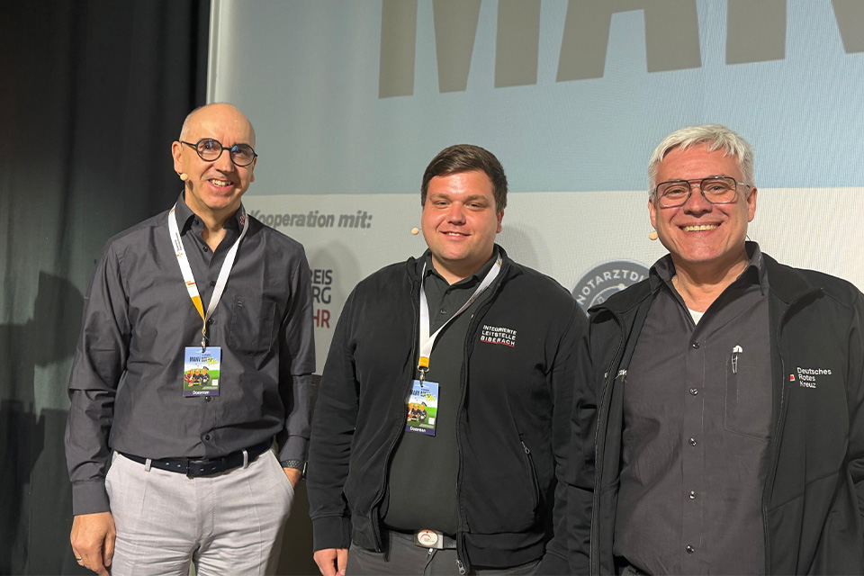 Drei Mitarbeiter des DRK Biberach stehen lächelnd auf einer Bühne.